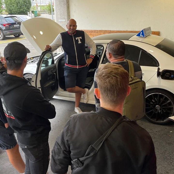 Fahrlehrer erklärt Fahrschülern das Auto